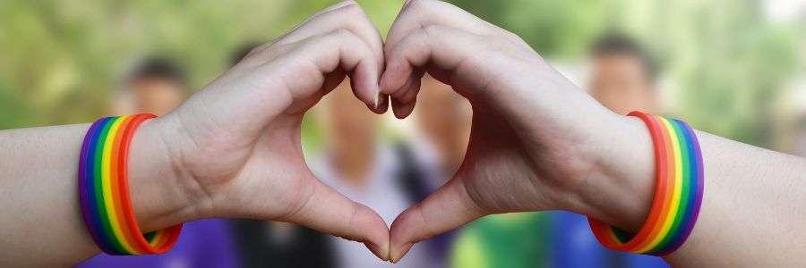 Hands making a heart shape with rainbow bracelets, symbolizing love, inclusion, and sharing love through the #all4Love campaign.