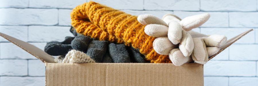 A donation box filled with warm gloves, scarves, and socks, ready to be given to those in need on Do1Give Day.