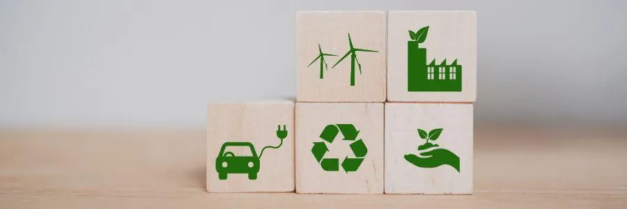 Wooden blocks with icons representing eco-friendly actions like electric vehicles, recycling, wind energy, and green industry.