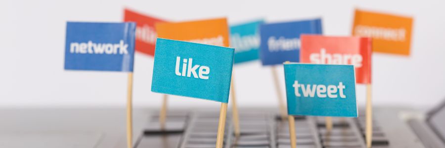Colorful flags with words like tweet, like, share, and network on a keyboard, symbolizing the power of social media and community engagement 