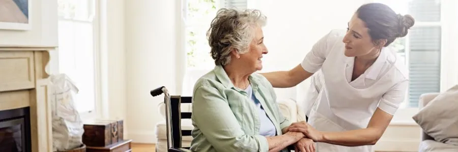 Smiling nurse offering support to an elderly woman in a wheelchair, capturing the spirit of National Making Life Beautiful Day