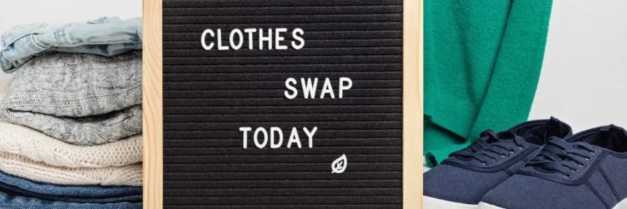 Clothes Swap Today sign surrounded by folded clothes and shoes, promoting sustainable giving and the bond of friendship through shared community efforts.