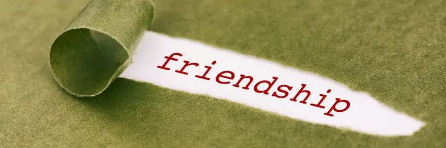 Word “friendship” revealed under torn green paper, symbolizing deep bonds