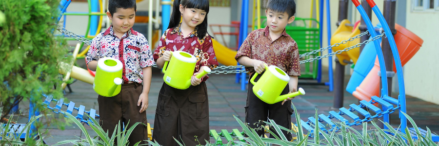 School students watering plants together, practicing eco-friendly environment habits outdoors.