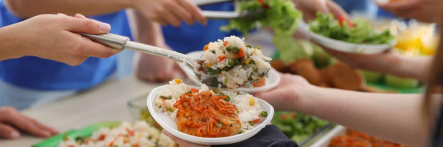 Volunteers serving meals during a community event promoting food sharing and connection