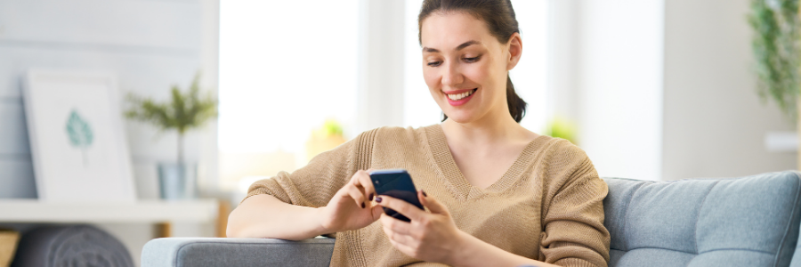 Woman smiling while sending a supportive text to Brighten Someone’s Day in 30 seconds 