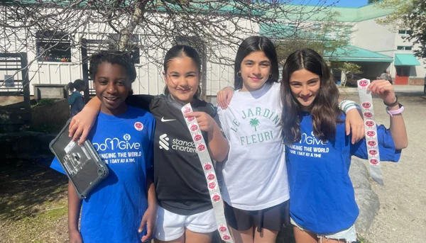 Students participating in Do1Give Day showing stickers after completing acts of giving at school.