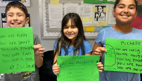 Students sharing appreciation notes with positive messages during a Do1Give Day classroom activity.