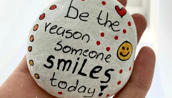 Painted rock with message “Be the reason someone smiles today” representing a small act of giving.