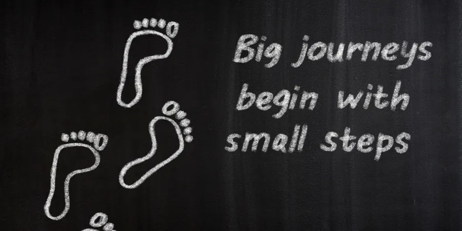 Chalk footprints beside the message “Big journeys begin with small steps,” symbolizing how everyday choices build leadership skills for students.