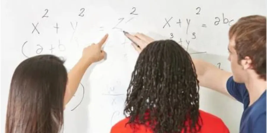 Students working together to solve a math problem on a whiteboard, demonstrating peer learning and teamwork.