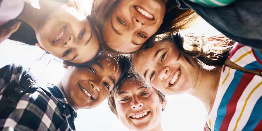 Diverse group of smiling students gathered in a circle, representing student belonging, supportive classrooms, and human connection.