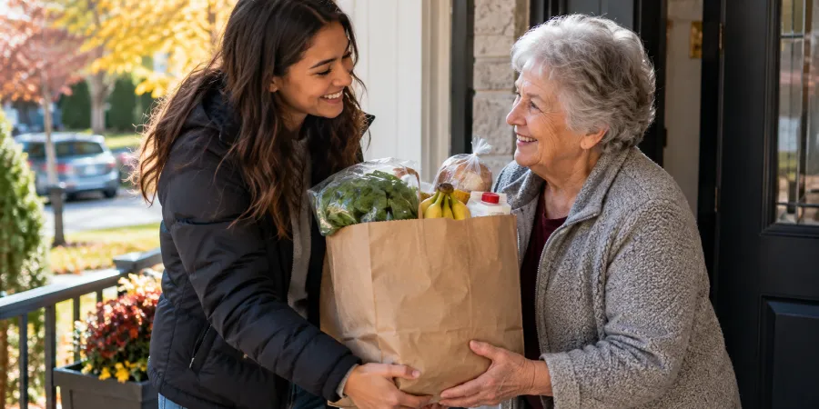 Young woman giving groceries to an older neighbour, showing the happiness and connection that can come from helping others.